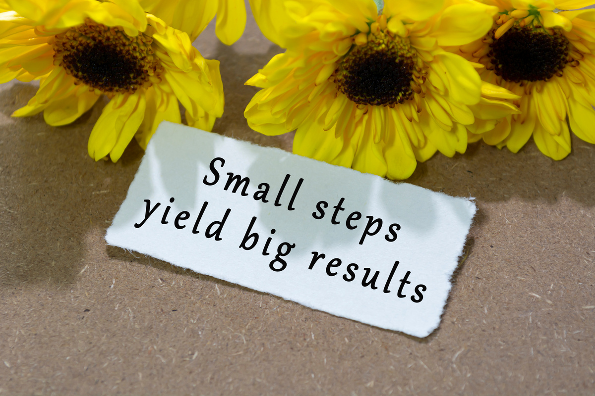 Motivational quote on torn white paper with sunflower on woo